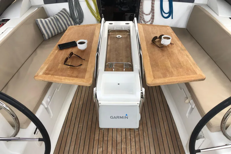  Yacht Photos Pics Cockpit of 2018 Jeanneau Sun Odyssey 419 with wooden tables, coffee cups, and sunglasses.