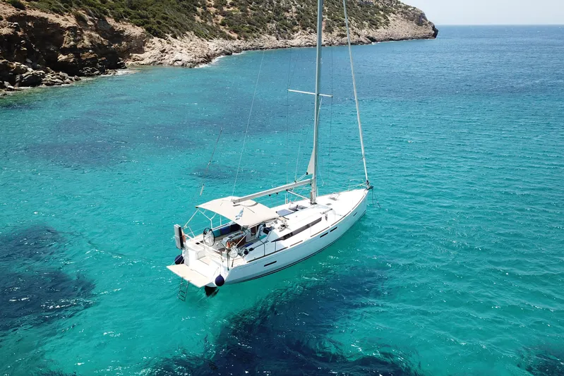  Yacht Photos Pics 2018 Jeanneau Sun Odyssey 419 sailing in clear turquoise waters near rocky coastline.