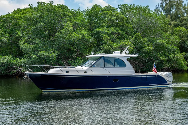 Yes Day Yacht Photos Pics 2021 Hinckley Sport Boat 40 X cruising on a serene waterway, surrounded by lush greenery.