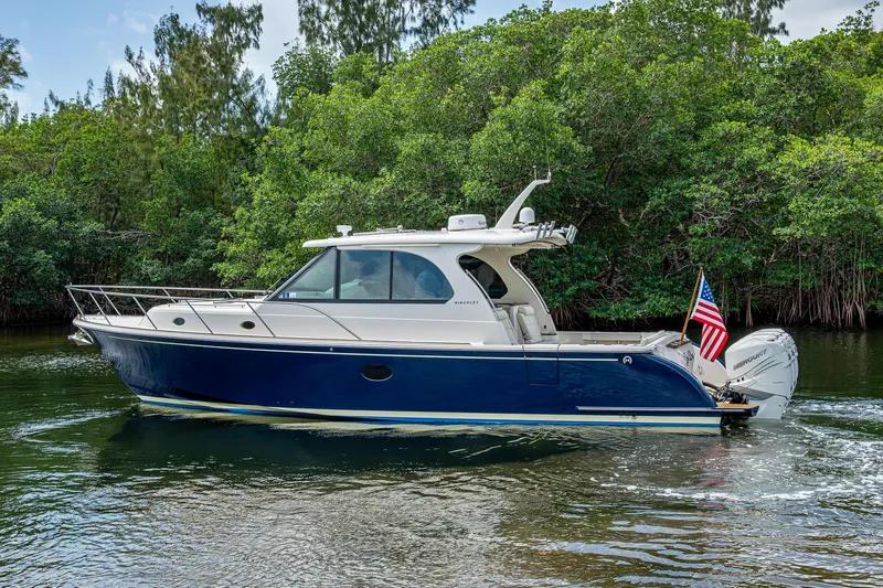 Yes Day Yacht Photos Pics 2021 Hinckley Sport Boat 40 X cruising on a serene waterway, surrounded by lush greenery.