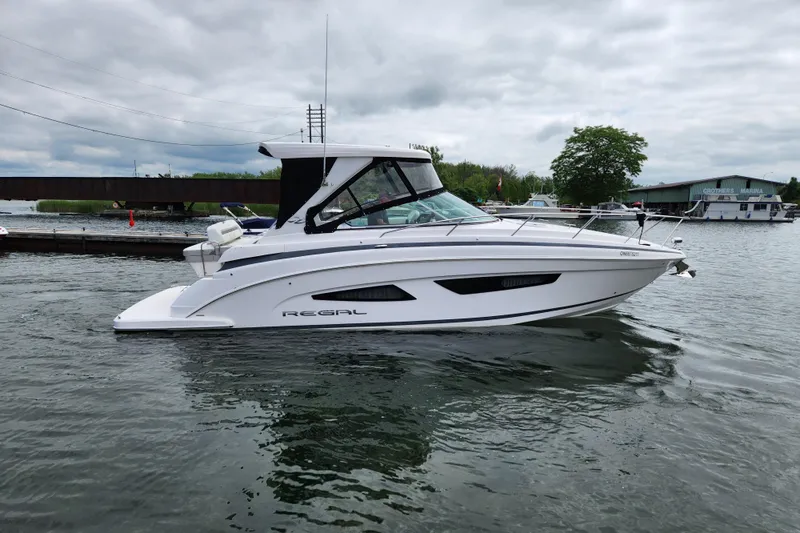 Loml Yacht Photos Pics 2020 Regal 33 Express boat on water near marina, overcast sky.