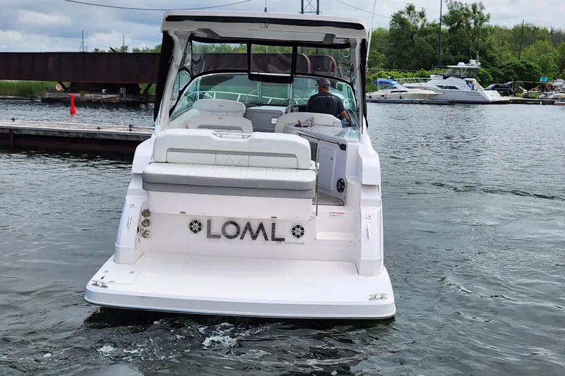 Loml Yacht Photos Pics 2020 Regal 33 Express boat on water, rear view, dock and trees in background.