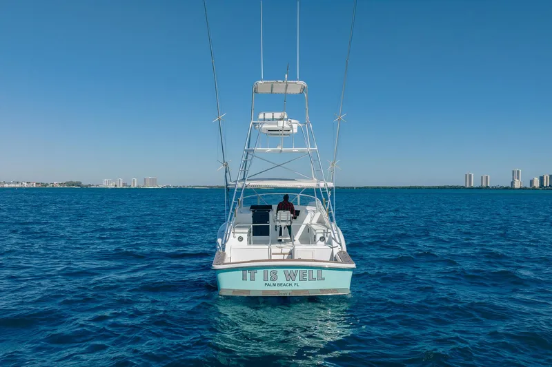 It Is Well Yacht Photos Pics 1997 Strike 42 Express boat on open water, clear sky, city skyline in background.