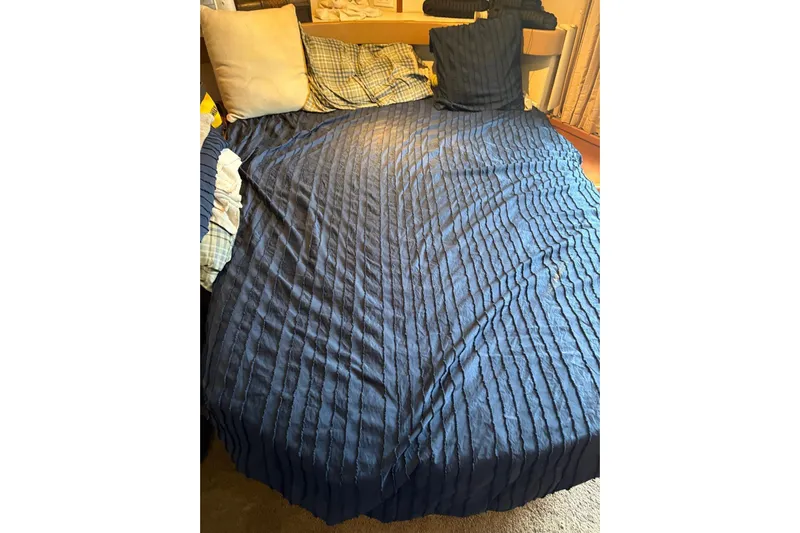 Reel Dezire Yacht Photos Pics Bed with blue textured cover and assorted pillows inside a 2005 Carver 41 Cockpit Motor Yacht.