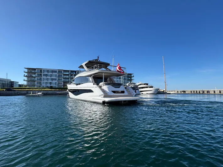  Yacht Photos Pics 2025 Princess Y80 yacht docked in marina, clear blue sky, modern waterfront buildings.