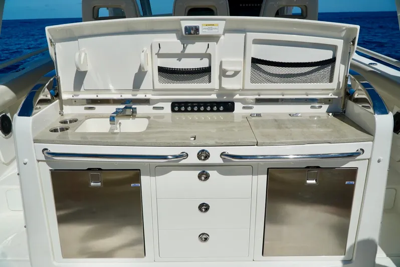  Yacht Photos Pics 2019 Boston Whaler 420 Outrage boat kitchen with sink, storage, and stainless steel appliances.