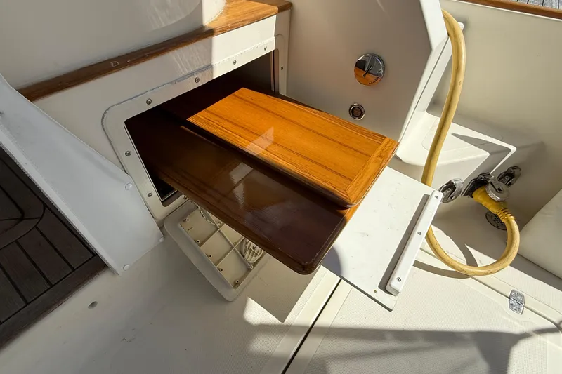 Tova Yacht Photos Pics 2007 Legacy Yachts 32 Sedan interior with wooden storage compartment and hose connection.