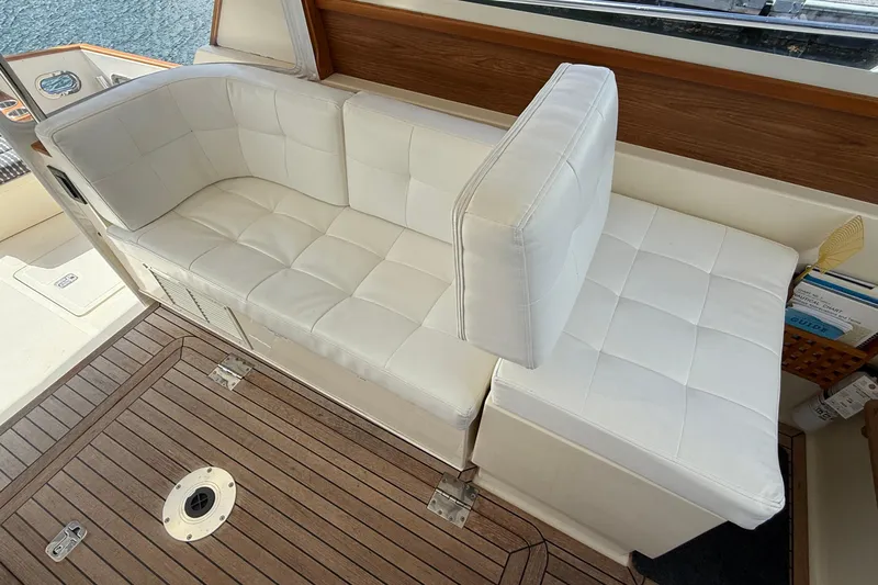Tova Yacht Photos Pics White cushioned seating on 2007 Legacy Yachts 32 Sedan with wooden flooring.