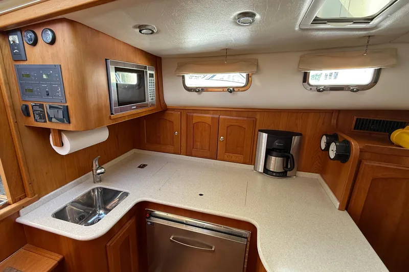 Tova Yacht Photos Pics 2007 Legacy Yachts 32 Sedan kitchen with wood cabinetry, sink, and appliances.