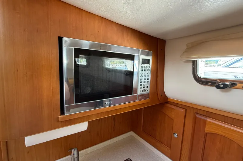 Tova Yacht Photos Pics Microwave in 2007 Legacy Yachts 32 Sedan interior, wooden cabinetry, and window view.