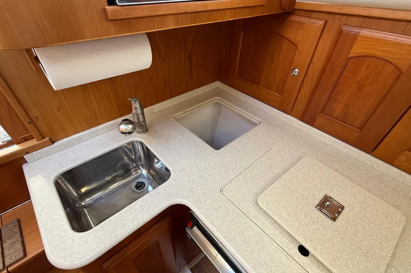 Tova Yacht Photos Pics 2007 Legacy Yachts 32 Sedan galley with sink, countertop, and wooden cabinetry.