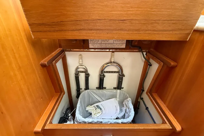 Tova Yacht Photos Pics Under-sink storage in 2007 Legacy Yachts 32 Sedan with plumbing and trash bin.