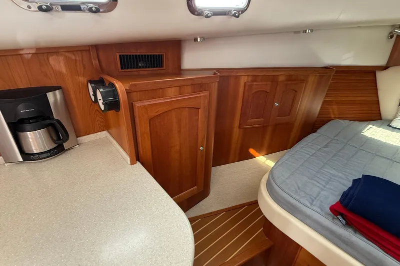 Tova Yacht Photos Pics 2007 Legacy Yachts 32 Sedan interior with wood cabinetry, countertop, and bed.
