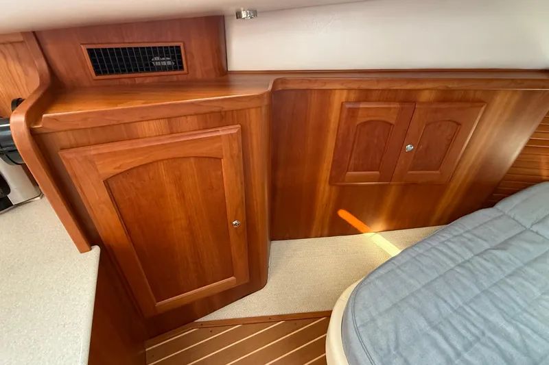 Tova Yacht Photos Pics Interior of 2007 Legacy Yachts 32 Sedan with wooden cabinetry and cozy bedding.
