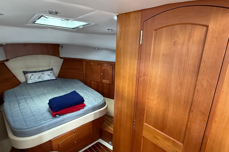 Tova Yacht Photos Pics Cozy cabin interior of 2007 Legacy Yachts 32 Sedan with wooden finishes and bedding.