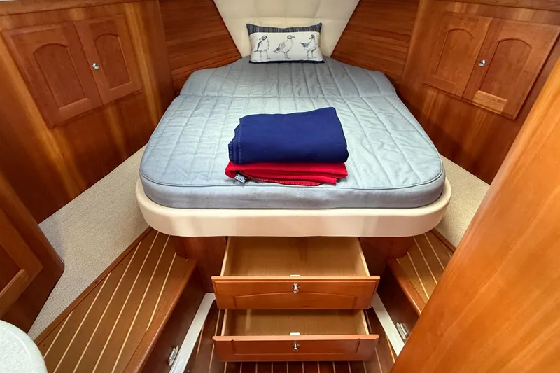 Tova Yacht Photos Pics Cozy cabin interior of 2007 Legacy Yachts 32 Sedan with bed and wooden storage.
