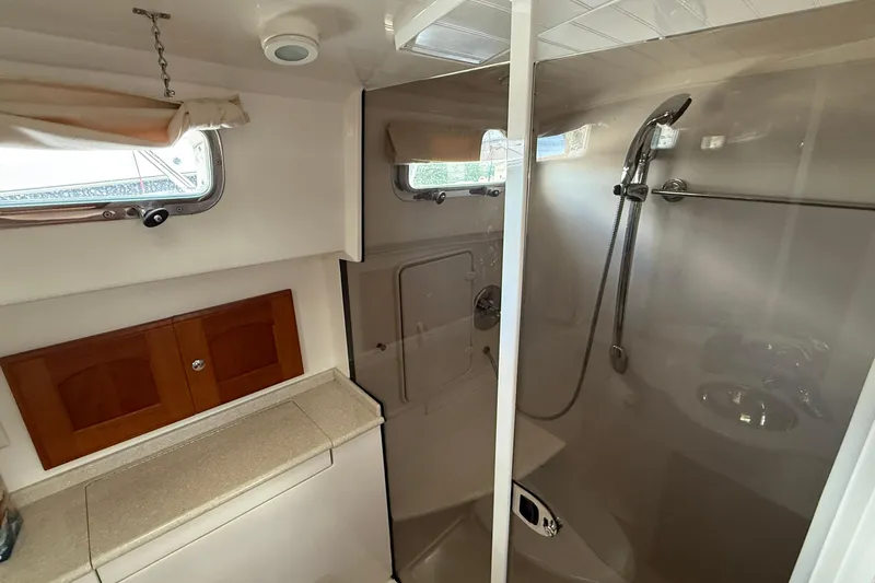 Tova Yacht Photos Pics 2007 Legacy Yachts 32 Sedan bathroom with shower, wooden cabinets, and porthole windows.
