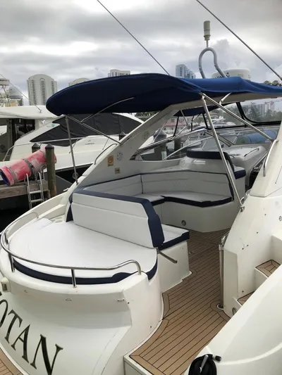 Hotan Yacht Photos Pics 2003 Sunseeker Portofino 46 yacht with blue canopy and white seating at a marina.