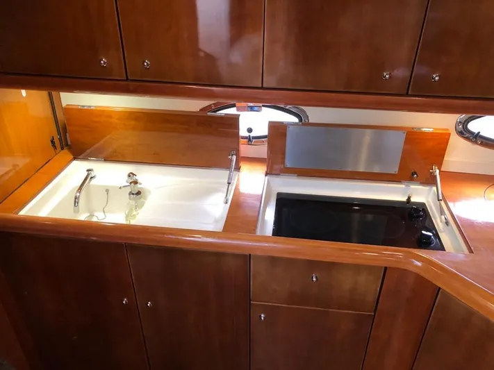 Hotan Yacht Photos Pics 2003 Sunseeker Portofino 46 yacht kitchen with wooden cabinets, sink, and stove.