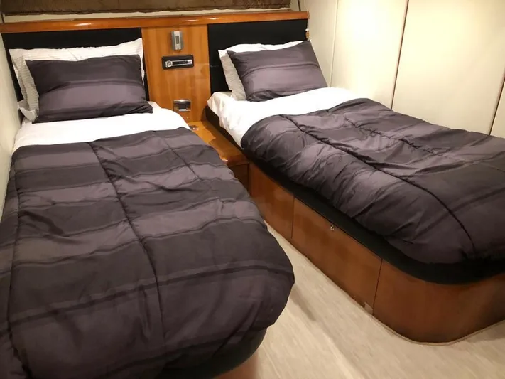 Hotan Yacht Photos Pics Twin beds in a 2003 Sunseeker Portofino 46 yacht cabin, featuring dark bedding and wood accents.