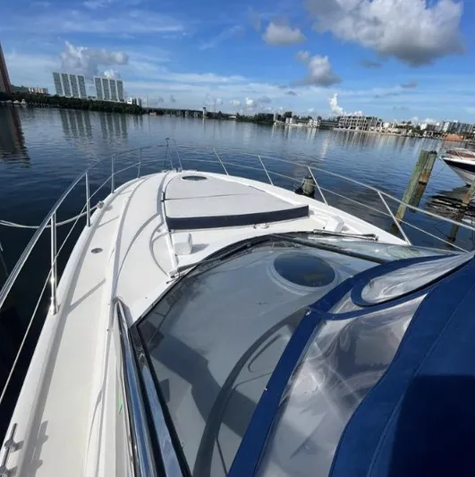 Hotan Yacht Photos Pics 2003 Sunseeker Portofino 46 yacht on calm water, clear sky, cityscape background.
