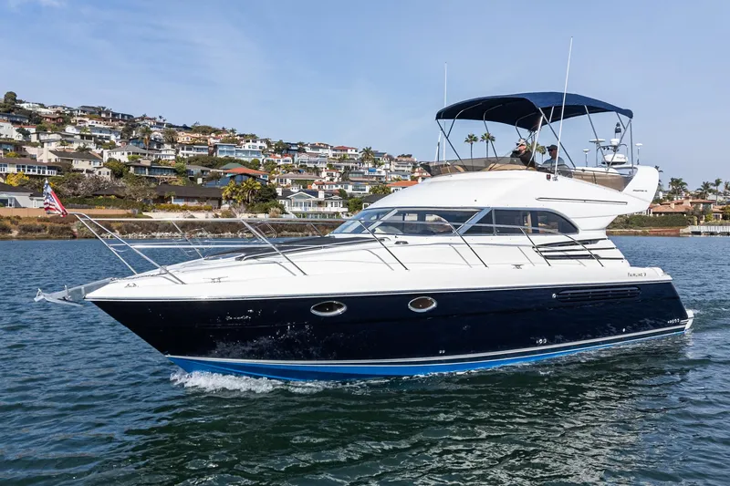 Phantom 42 Yacht Photos Pics 1998 Fairline Phantom 42 yacht cruising on water near coastal homes.