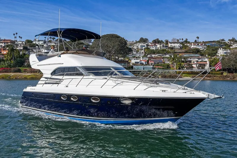 Phantom 42 Yacht Photos Pics 1998 Fairline Phantom 42 yacht cruising on a sunny day near coastal homes.