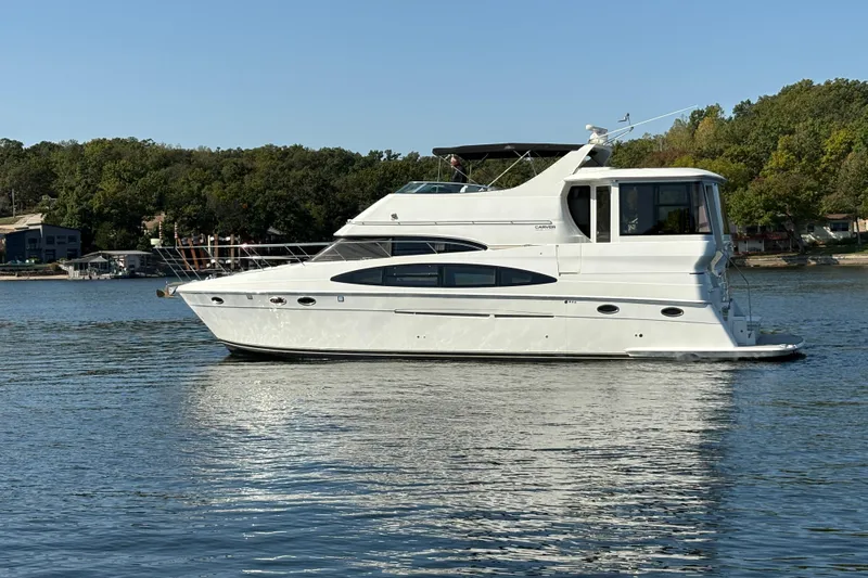  Yacht Photos Pics 2002 Carver 506 Motor Yacht on a serene lake with lush green shoreline.