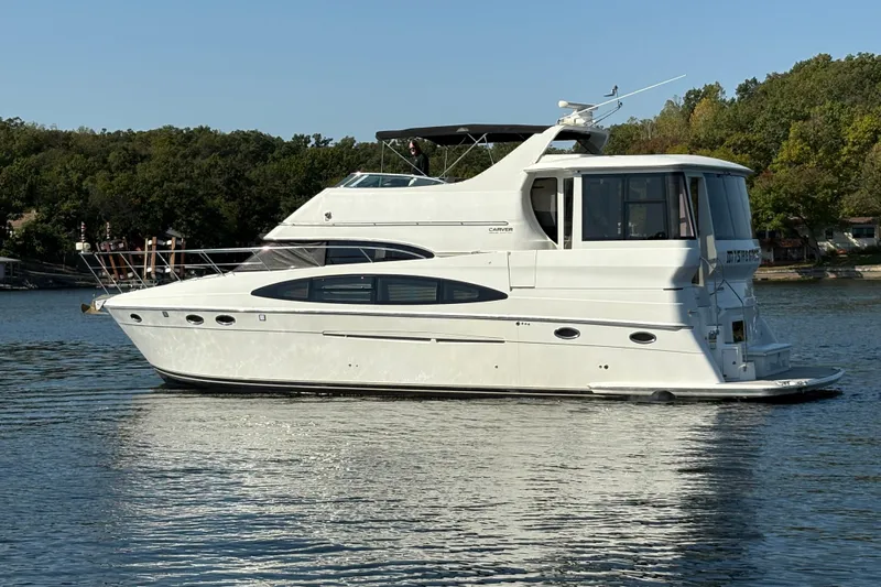  Yacht Photos Pics 2002 Carver 506 Motor Yacht on a serene lake, surrounded by lush greenery.