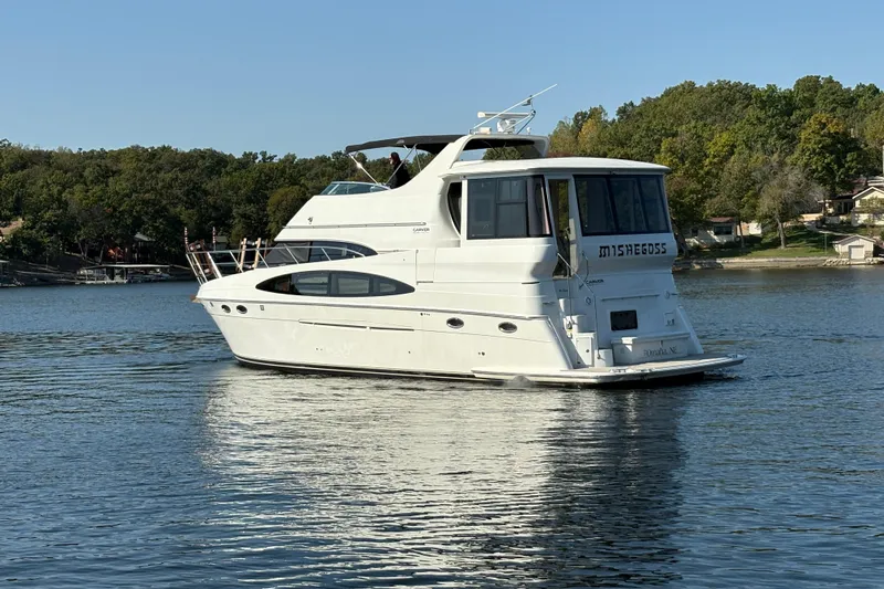  Yacht Photos Pics 2002 Carver 506 Motor Yacht cruising on a serene lake with lush green shoreline.