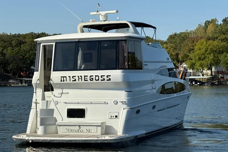  Yacht Photos Pics 2002 Carver 506 Motor Yacht on a serene lake, surrounded by lush trees.