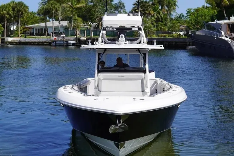  Yacht Photos Pics 2016 Everglades 435 Center Console boat on calm water, surrounded by lush greenery.