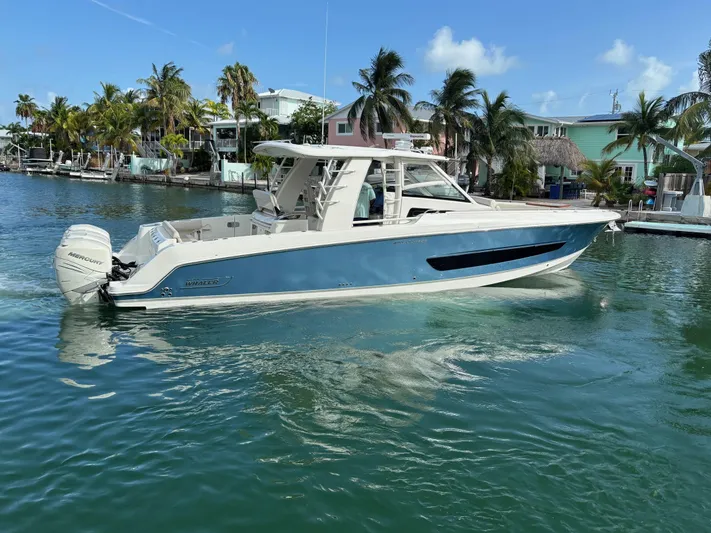 Demo Diamond Yacht Photos Pics 2017 Boston Whaler 420 Outrage boat on clear water near palm trees and houses.