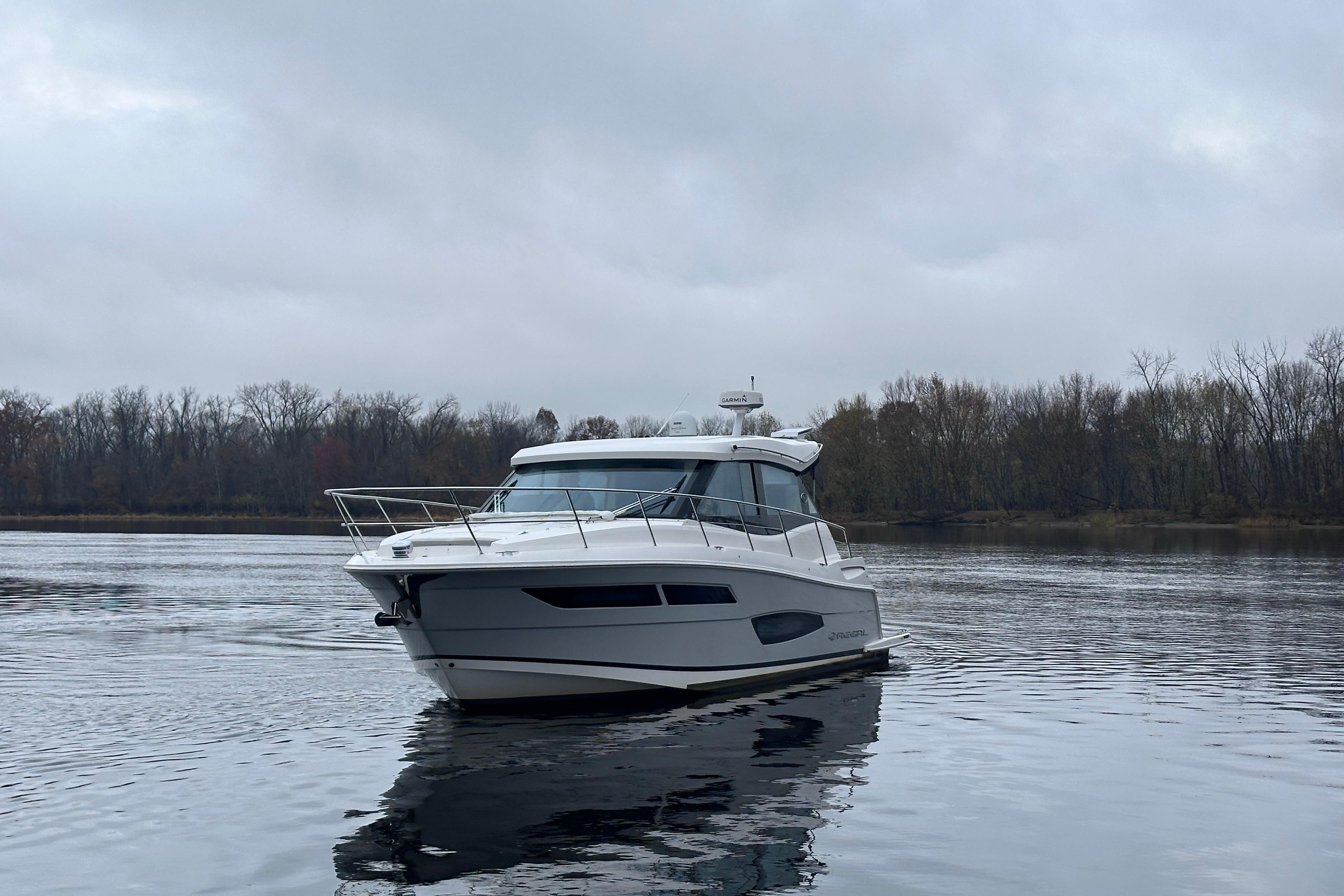 2021 Regal 38 XO yacht on a calm lake under overcast skies.