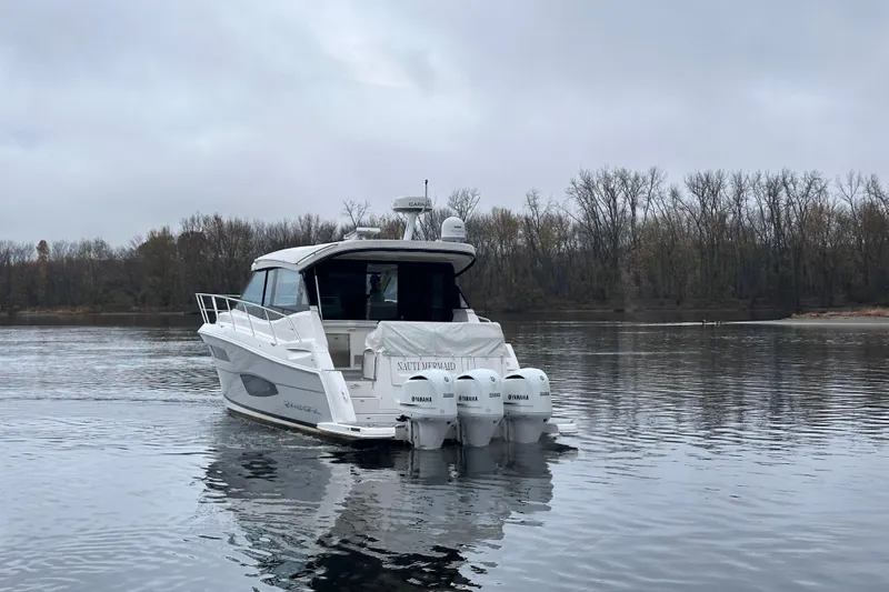  Yacht Photos Pics 2021 Regal 38 XO boat on calm water with overcast sky and wooded shoreline.