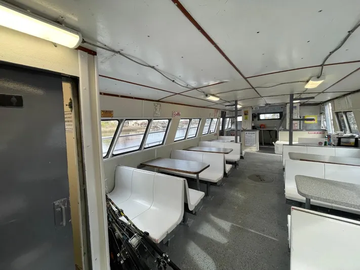 Super Voyager III Yacht Photos Pics Interior of a 1972 Swiftships commercial passenger vessel with white seating and large windows.