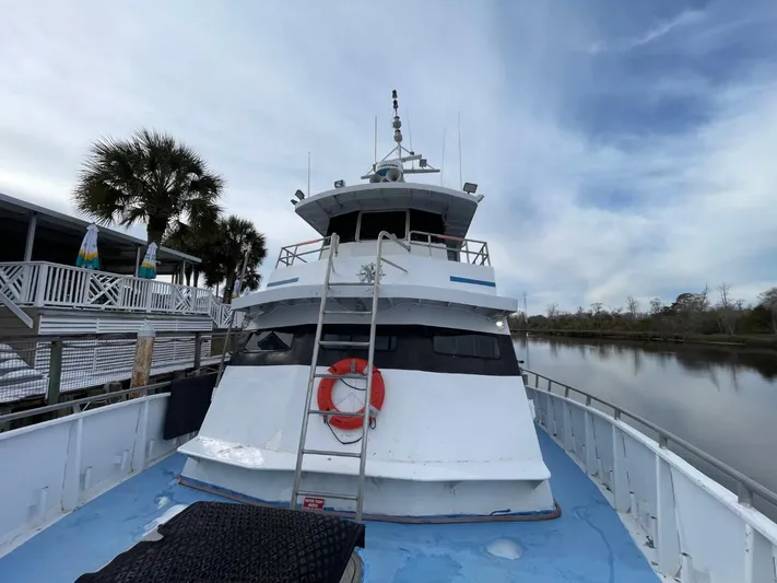 Super Voyager III Yacht Photos Pics 1972 Swiftships commercial passenger boat docked by a riverside with palm trees.
