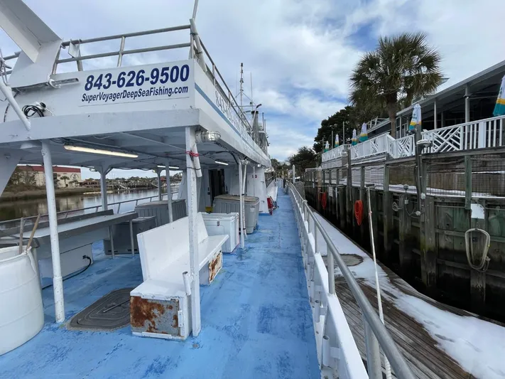 Super Voyager III Yacht Photos Pics 1972 Swiftships commercial passenger boat docked, featuring blue deck and contact information for deep sea fishing.