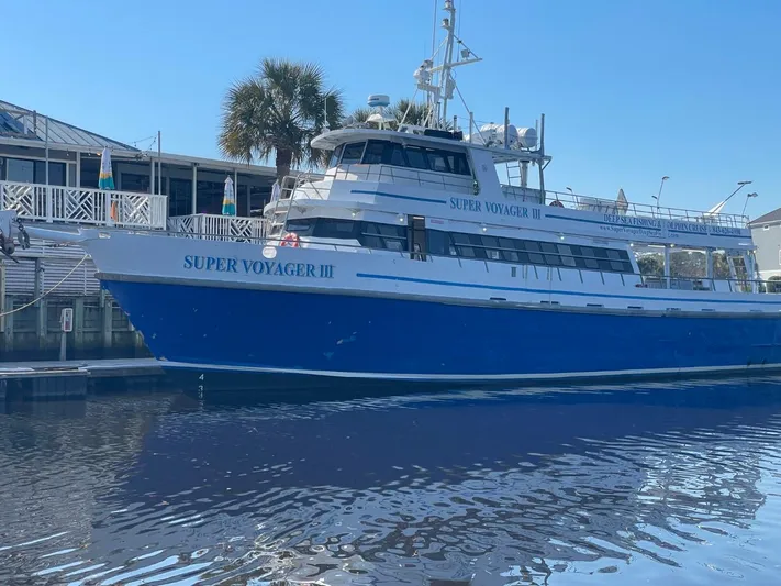 Super Voyager III Yacht Photos Pics Swiftships 1972 Commercial Passenger boat, "Super Voyager III," docked by a waterfront building.
