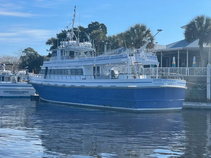 Super Voyager III Yacht Photos Pics 1972 Swiftships Commercial Passenger boat docked by a waterfront building.
