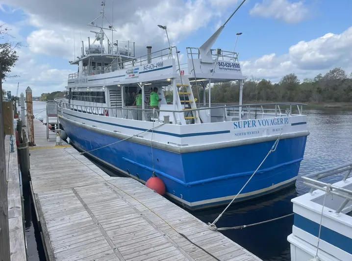 Super Voyager III Yacht Photos Pics Blue and white 1972 Swiftships commercial passenger boat docked by a wooden pier.
