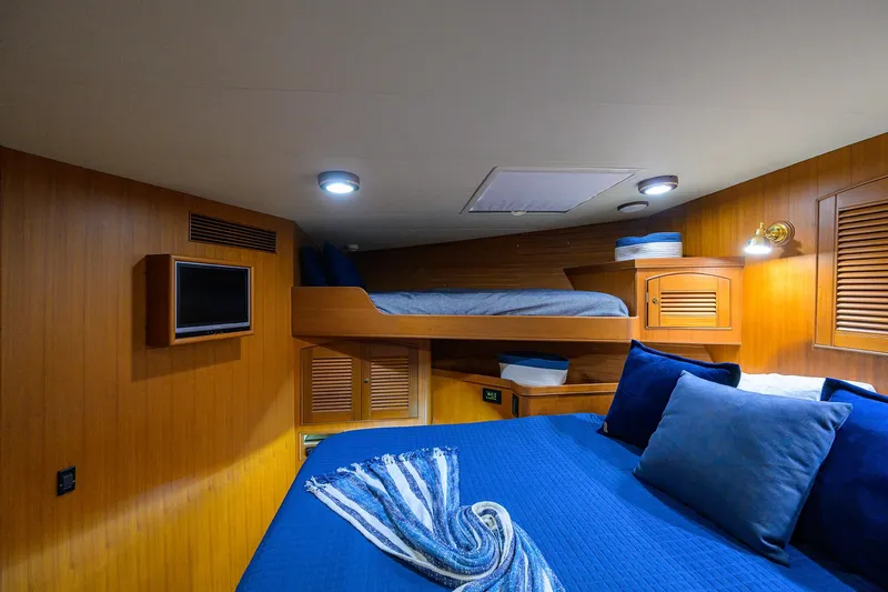 Bandol Yacht Photos Pics Cozy cabin interior of 2006 Marlow 78E yacht with wooden walls and blue bedding.