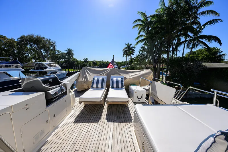 Bandol Yacht Photos Pics Luxury Marlow 78E yacht deck with sun loungers, palm trees, and clear blue sky.