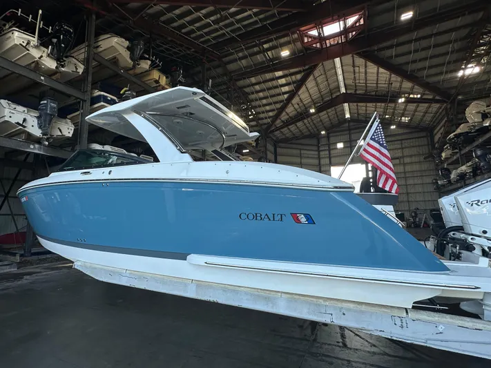  Yacht Photos Pics 2022 Cobalt R33 boat in a warehouse, featuring a sleek blue and white design.