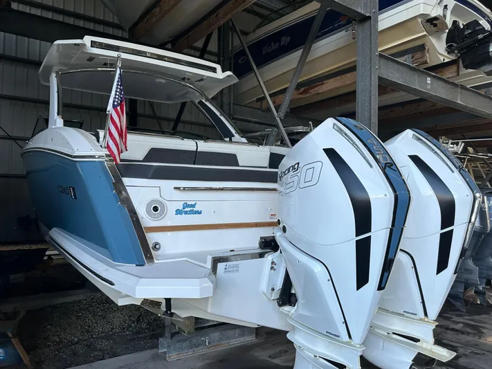  Yacht Photos Pics 2022 Cobalt R33 boat with twin outboard engines in storage, featuring an American flag.