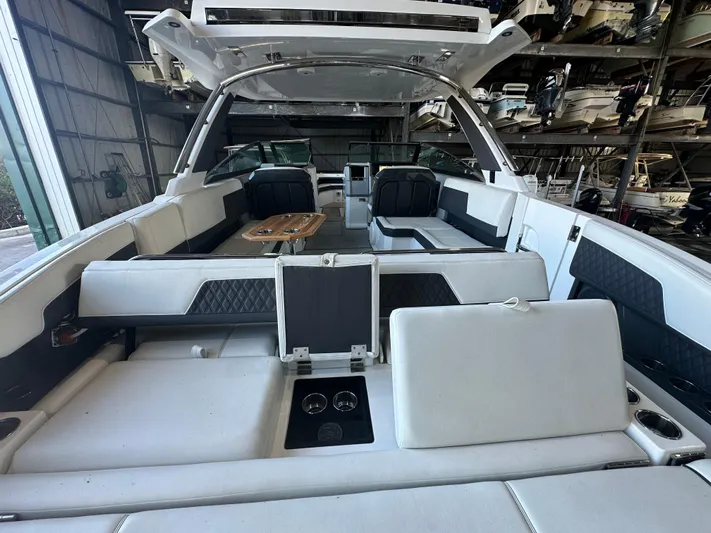  Yacht Photos Pics 2022 Cobalt R33 boat interior with white seating and wooden table in storage facility.