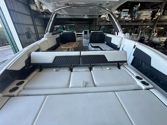  Yacht Photos Pics 2022 Cobalt R33 boat interior with white seating and wooden table in a storage facility.