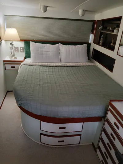  Yacht Photos Pics Cozy bedroom in 1986 Bertram 46 Flybridge Motor Yacht with bed, lamp, and storage drawers.