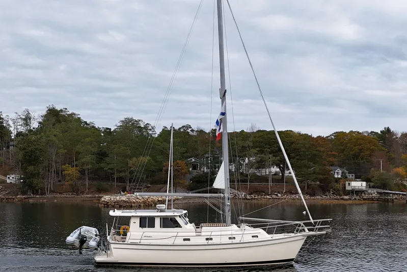  Yacht Photos Pics 2008 Island Packet SP Cruiser sailboat on calm water, surrounded by lush greenery.