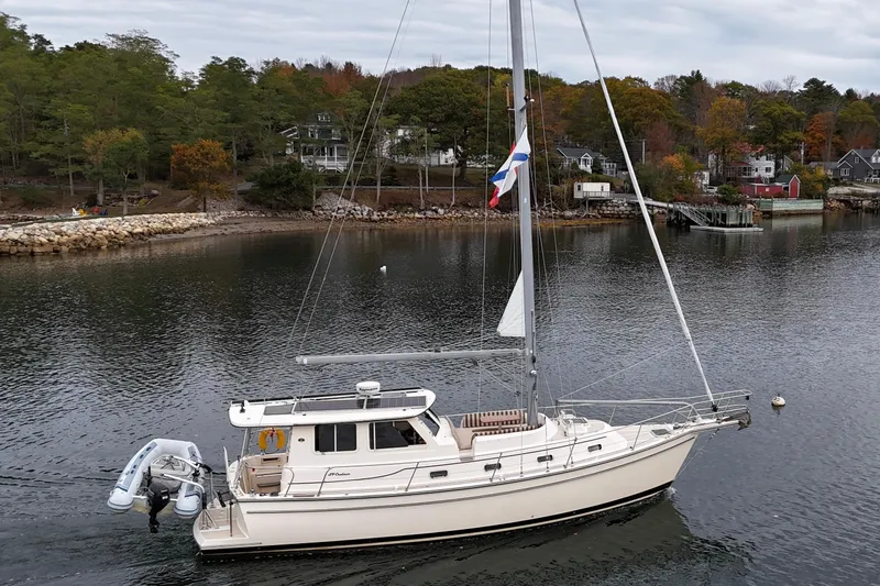  Yacht Photos Pics 2008 Island Packet SP Cruiser sailboat on calm water near a wooded shoreline.